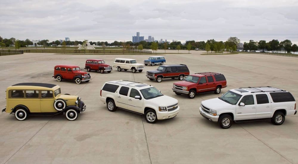 A group of used Chevrolet Suburbans is shown parked on concrete. 