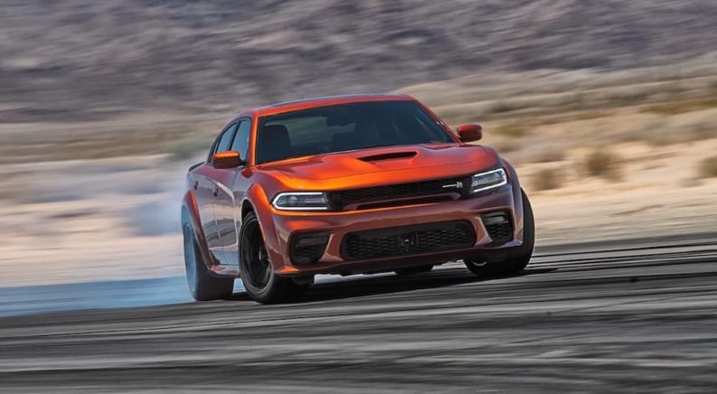 An orange 2022 Dodge Charger Scat Pack WideBody is shown from the front while sliding.