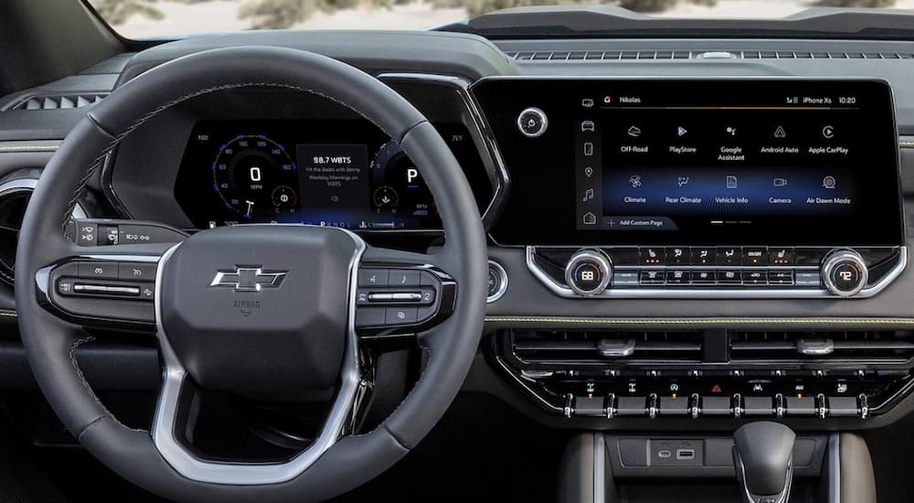 The black interior of a 2023 Chevy Colorado shows the steering wheel and infotainment screen.