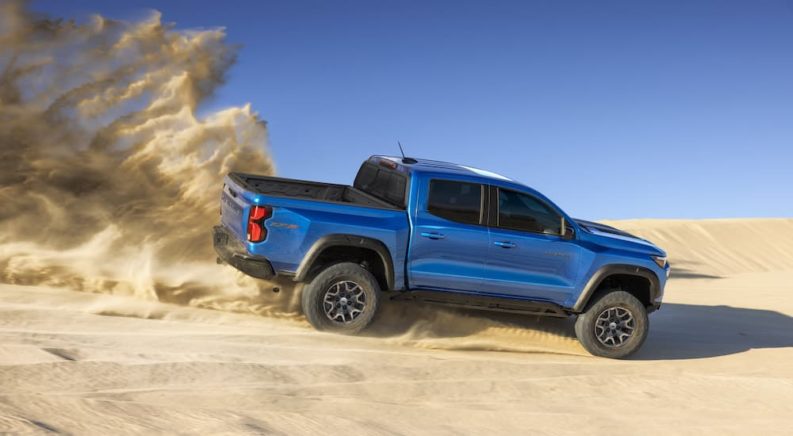 A blue 2023 Chevy Colorado ZR2 is shown from the side while driving on a dune.