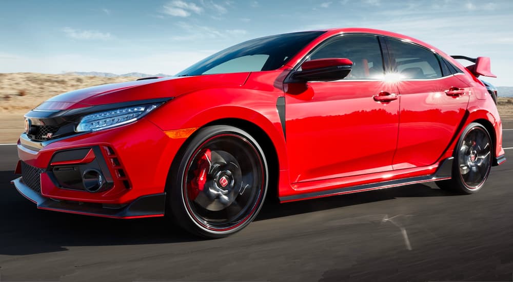 A red 2021 Honda Civic Type R is shown on an open road after leaving a car dealership.