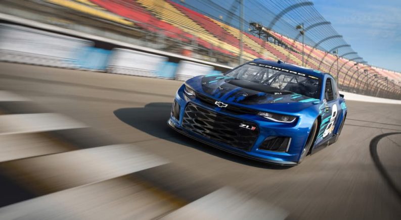 A blue 2018 Chevy Camaro ZL1 is shown driving on a racetrack.