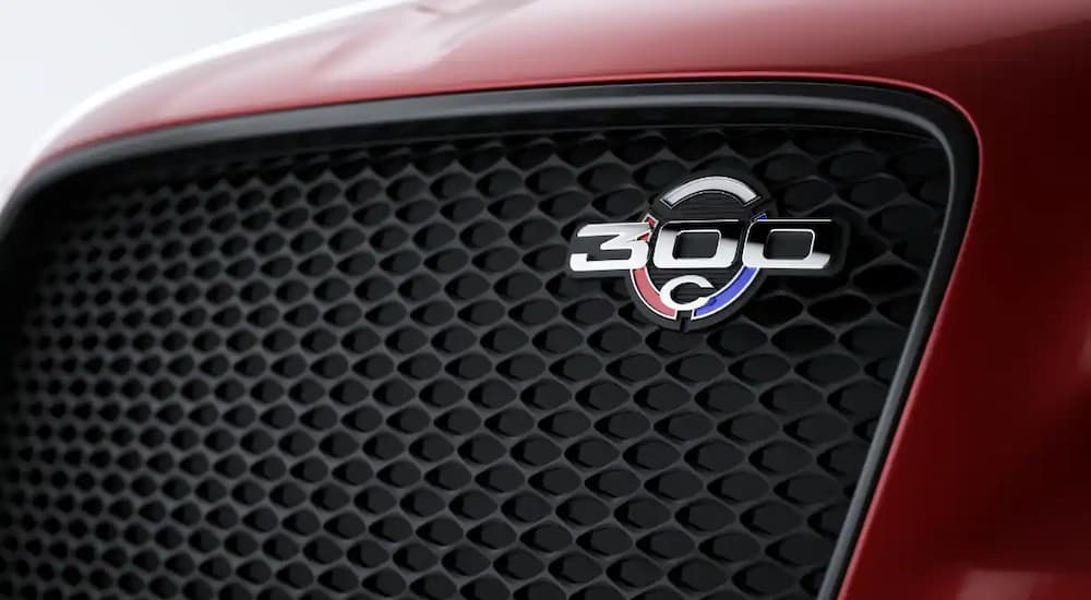 A close up shows the 300C badge on the grille of a red 2023 Chrysler 300C.
