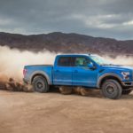 A blue 2020 Ford F-150 is shown from the side kicking up dust on the way to a Ford F-150 dealer.