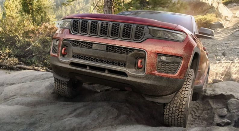A red 2022 Jeep Grand Cherokee Trailhawk is shown off-roading.