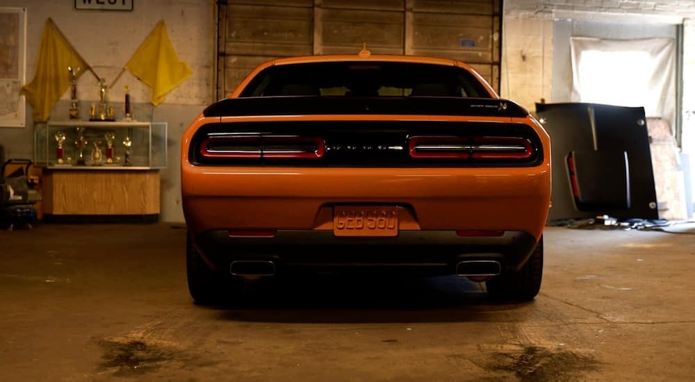 A popular used Dodge Challenger for sale, an orange 2020 Dodge Challenger is shown parked in a garage.