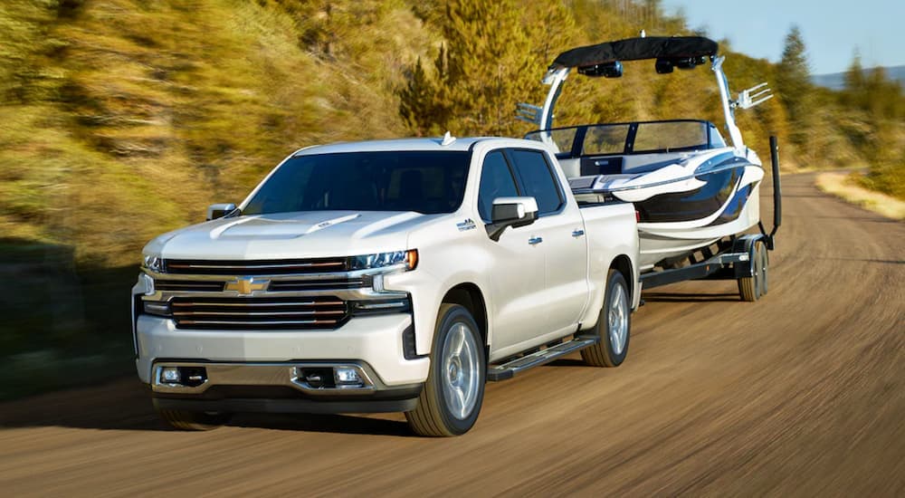 A white 2021 Chevy Silverado 1500 is shown towing a boat.