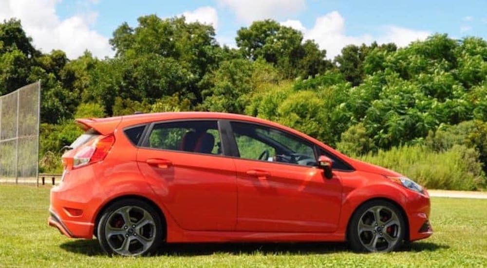 An orange 2015 Ford Fiesta ST is shown from the side while parked in a field.