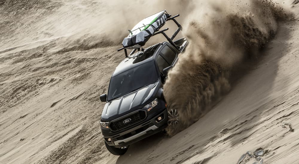 A black 2023 Ford Ranger is shown from the front while driving on a sand dune.