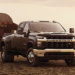 A black 2023 Chevy Silverado 3500 HD is shown parked in a field towing a trailer.