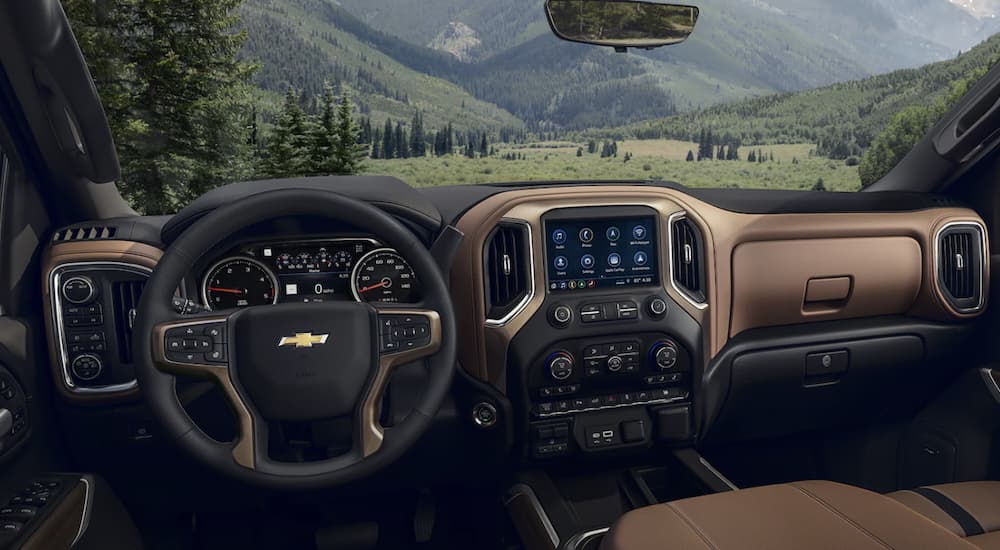 The black and brown interior of a 2023 Chevy Silverado 3500 HD shows the steering wheel and infotainment screen.