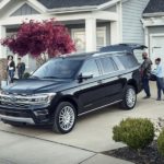 A black 2023 Ford Expedition Platinum is shown parked in a driveway as a family loads up cargo.