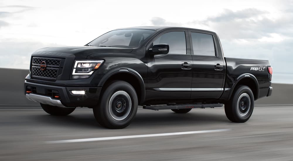 A black 2023 Nissan Titan is shown from the side driving on an open road.