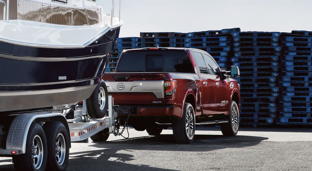 A red 2023 Nissan Titan is shown towing a boat.