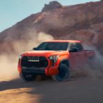 An orange 2023 Toyota Tundra TRD Pro is shown kicking up dust.