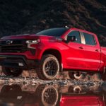 A red 2023 Chevy Silverado 1500 Z71 is shown parked on rocks next to a lake.