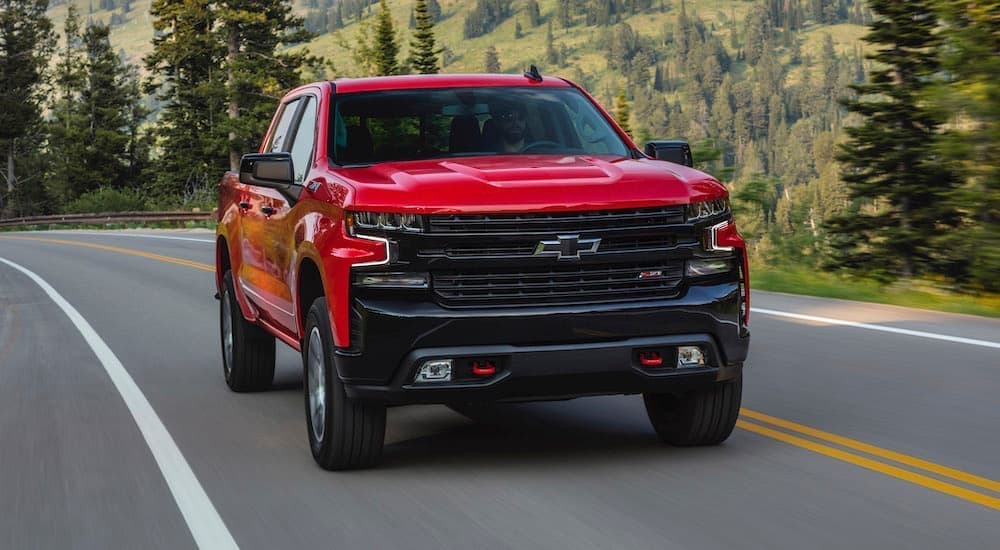 A red 2020 Chevy Silverado 1500 LT Trail Boss is shown driving on an open road. 