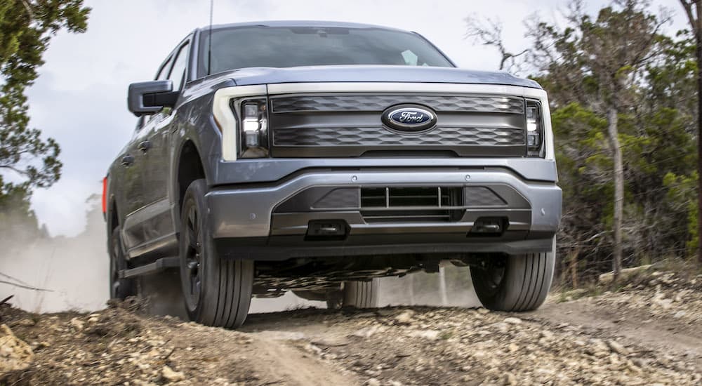 A silver 2023 Ford F-150 Lightning is shown from the front at a low angle.