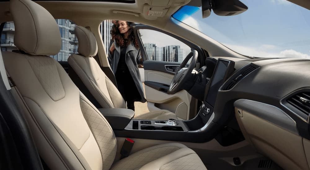 A woman is shown getting into the driver's seat of a 2023 Ford Edge Titanium after leaving a Ford Edge dealer.