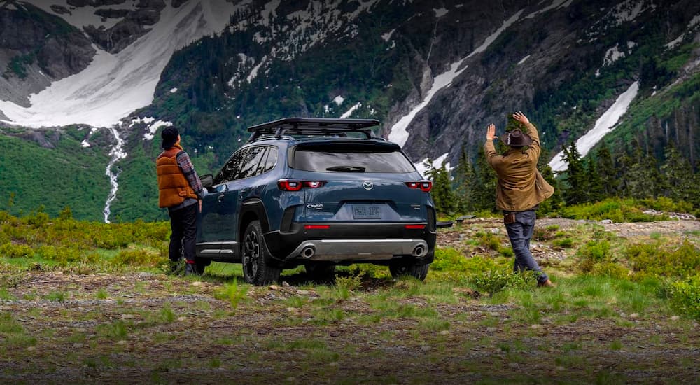 A grey 2023 Mazda CX-50 is shown parked in front of snowy mountains.