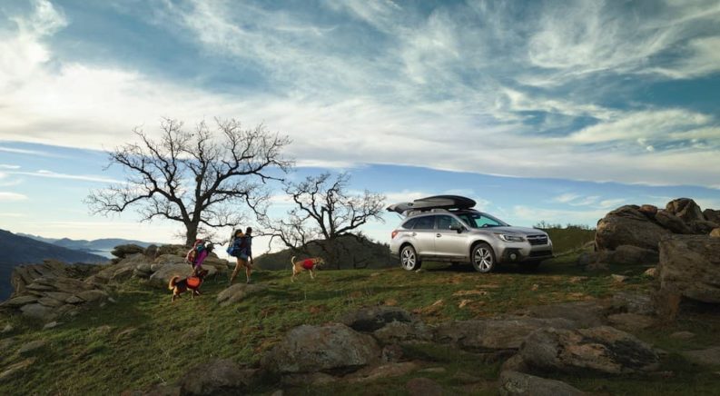 A silver 2018 Subaru Outback is shown parked near hikers.