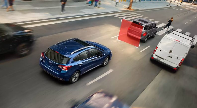 A blue 2023 Subaru Impreza is shown displaying a forward collision warning after visiting a Subaru dealer.