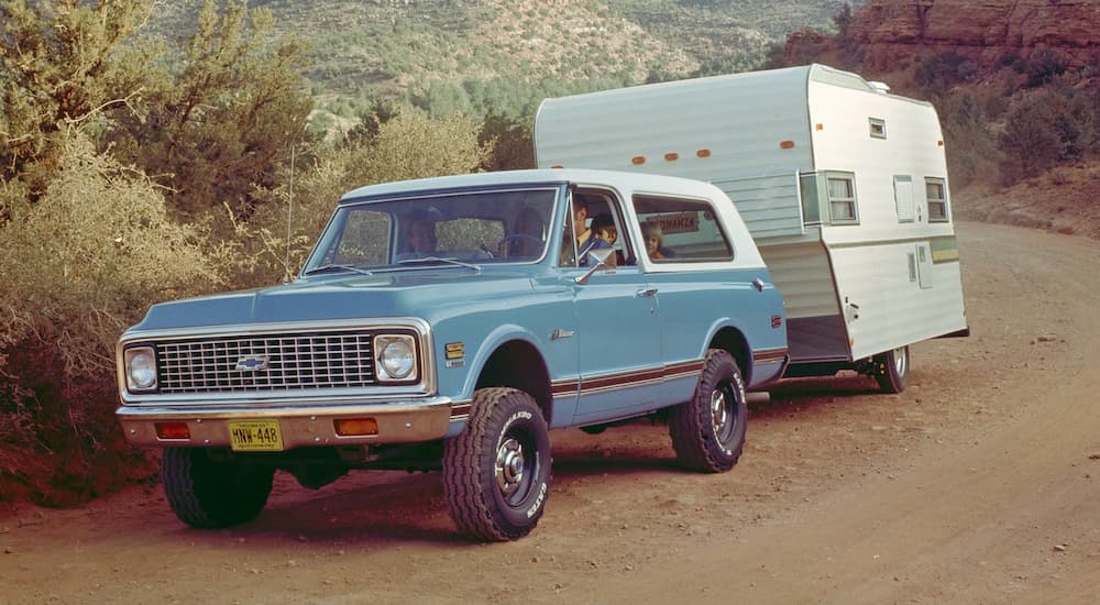 A turquoise 1969 Chevy K5 Blazer is shown towing a trailer.