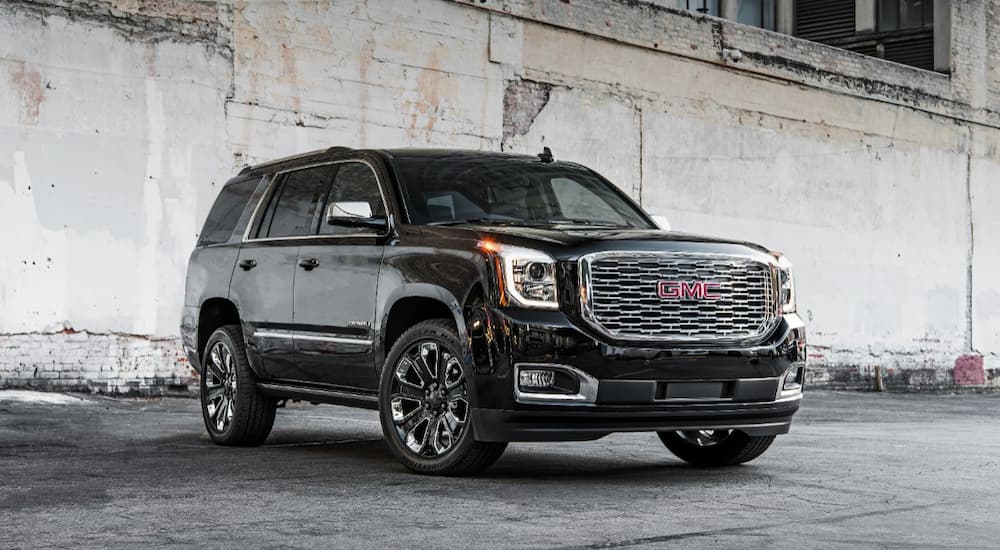 A black 2019 GMC Yukon is shown parked next to a concrete wall.