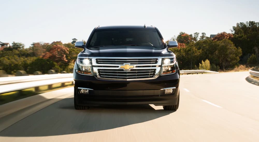 A black 2020 Chevy Suburban is shown from the front driving on a highway.