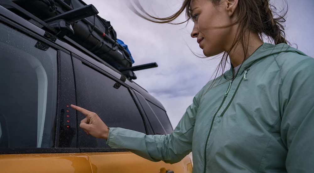 A woman is shown using the SecuriCode Entry Pad on a yellow 2022 Ford Bronco Sport.