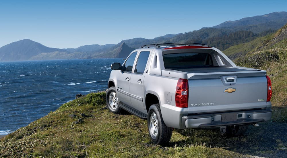 A silver 2013 Chevy Avalanche is shown from the rear after leaving a used truck dealer.