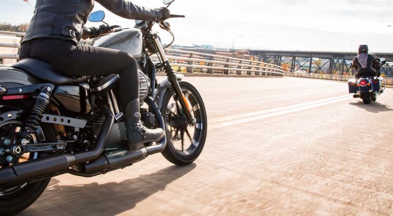 Two black 2022 Harley-Davidson Iron 883 are shown riding on a bridge.