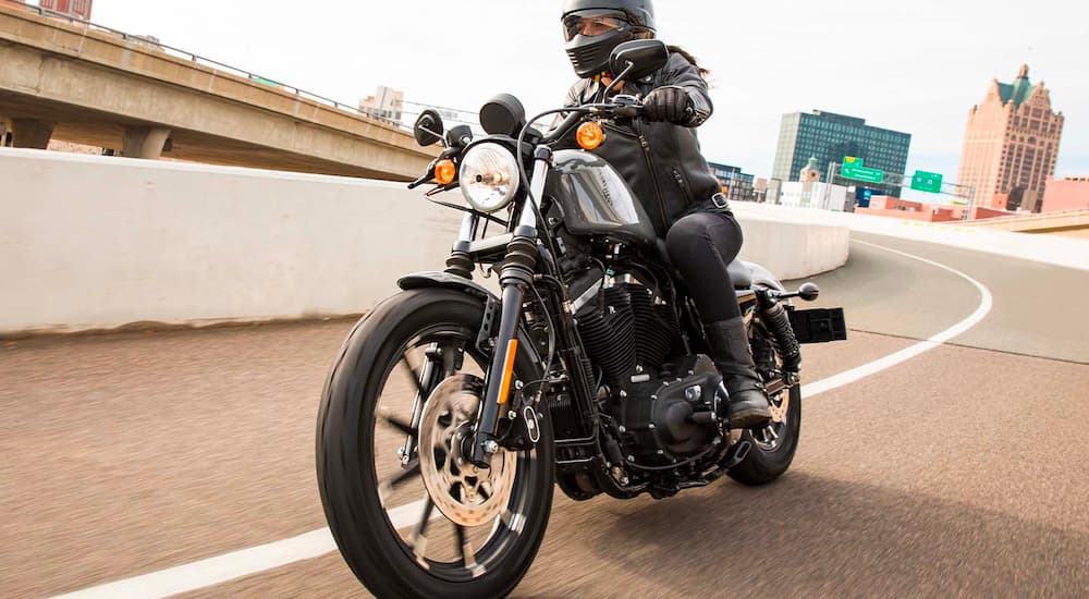 A close up shows a 2022 Harley-Davidson Iron 883 driving on a ramp.