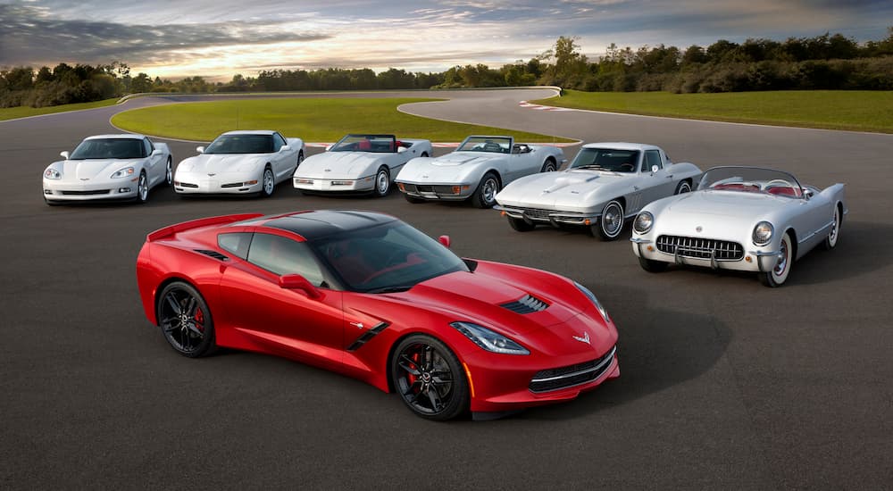 A red 2014 Chevy Corvette is shown in front of multiple white Corvettes.