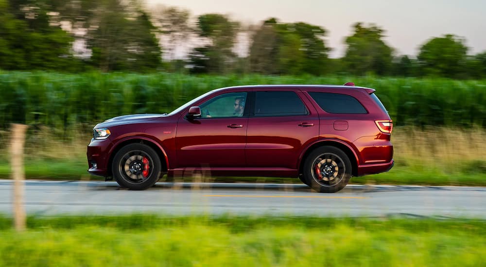 A maroon 2022 Dodge Durango SRT 392 is shown from the side driving past a field.