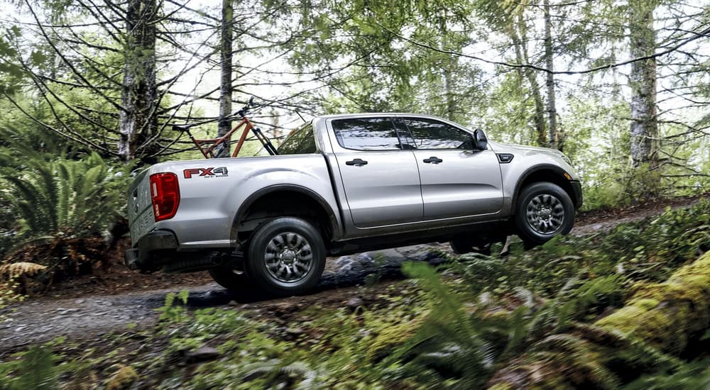 A silver 2023 Ford Ranger XLT is shown from the side driving through a forest.