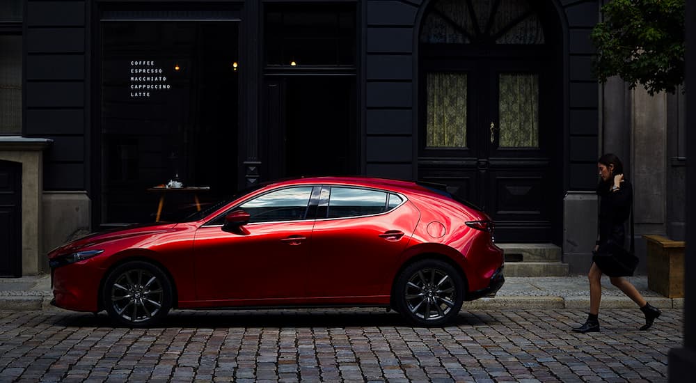 A red 2023 Mazda3 is shown from the side in front of a coffee shop.