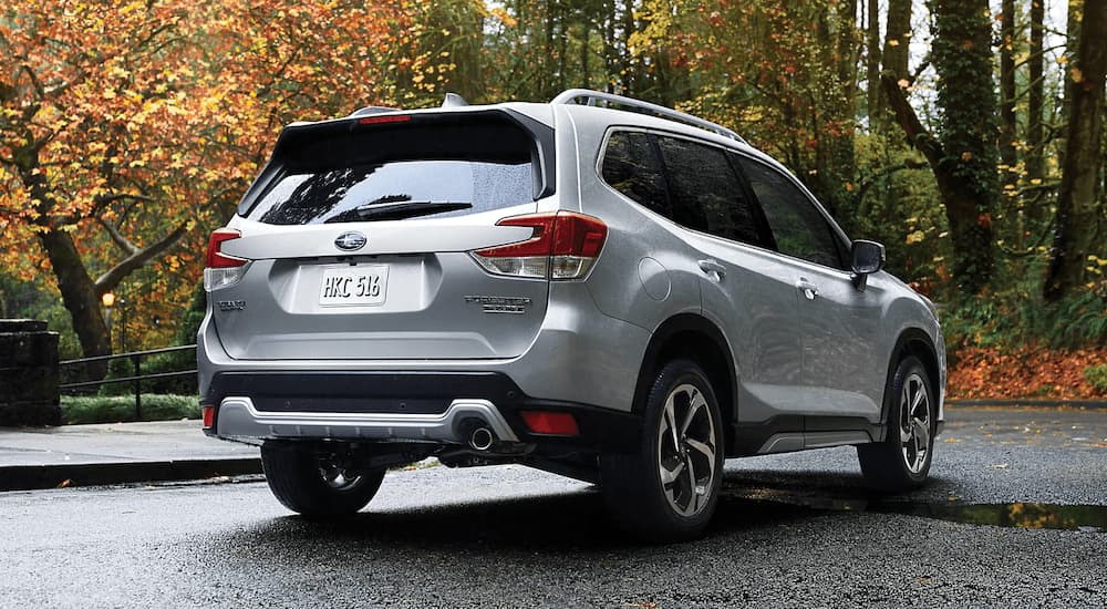 A silver 2023 Subaru Forester Touring is shown from the rear parked in an empty lot.