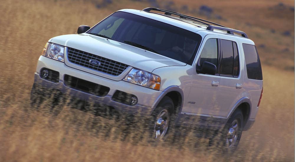 A white 2002 Ford Explorer is shown driving through a field.