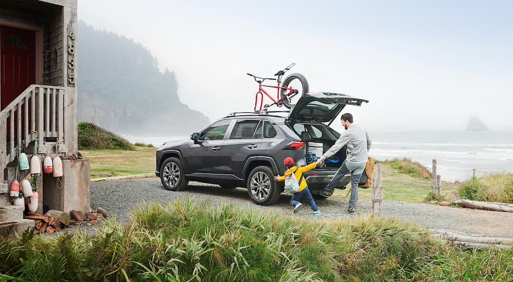 A family is shown putting cargo into the back of a grey 2020 Toyota RAV4.