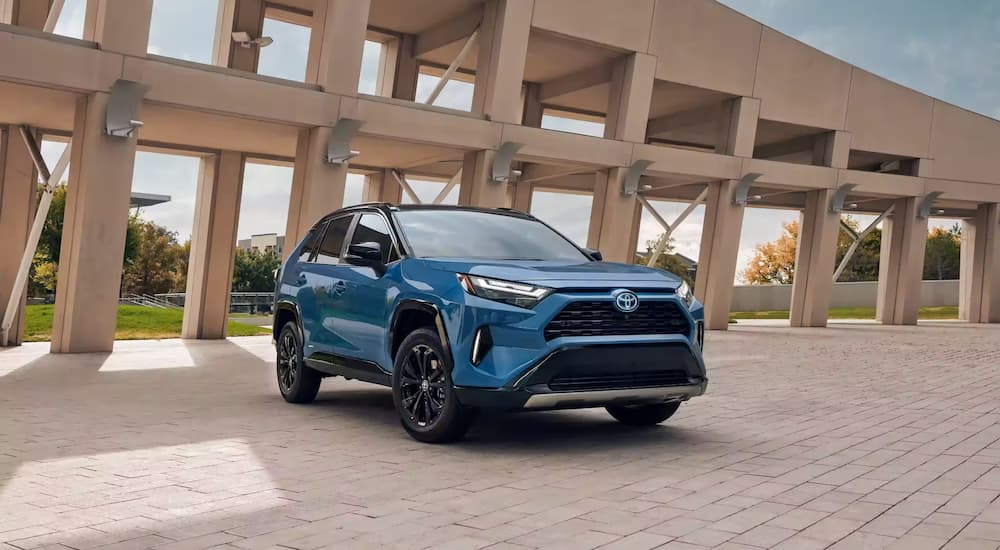 A blue 2023 Toyota RAV4 Hybrid XSE is shown parked near a concrete structure.
