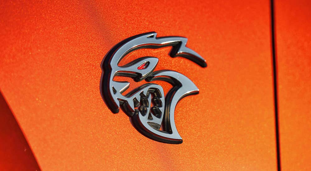 The badge of an orange 2023 Dodge Challenger Hellcat is shown in close-up.