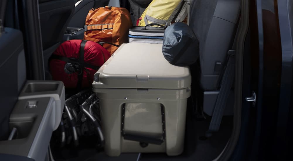 The interior storage of a 2023 Ford F-150 is shown full of camping cargo.