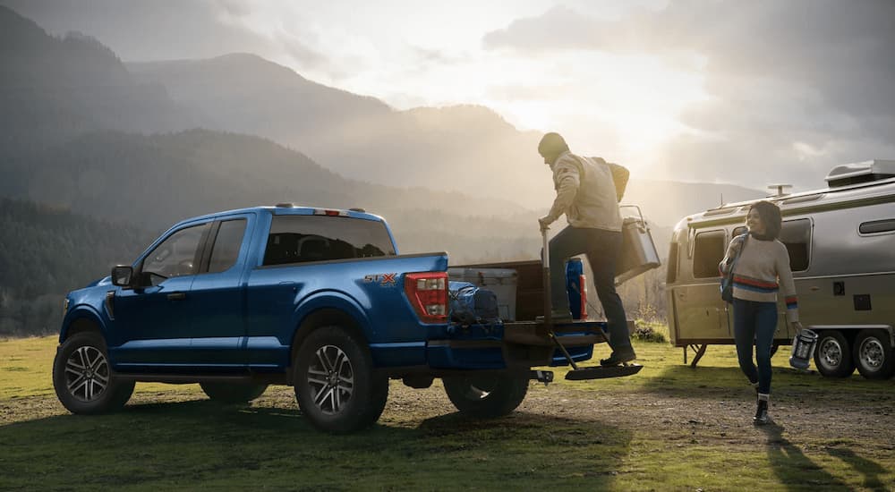 A man is shown stepping into the bed of a 2023 Ford F-150 STX at a campsite.