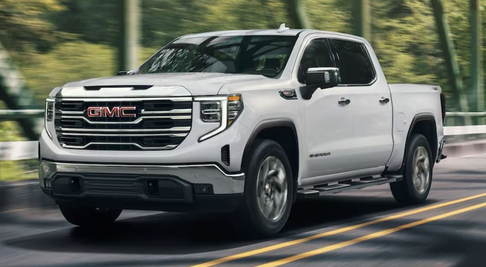 A white 2023 GMC Sierra 1500 is shown from the front driving on an open road during a 2023 GMC Sierra 1500 vs 2023 Chevy Silverado 1500 comparison.