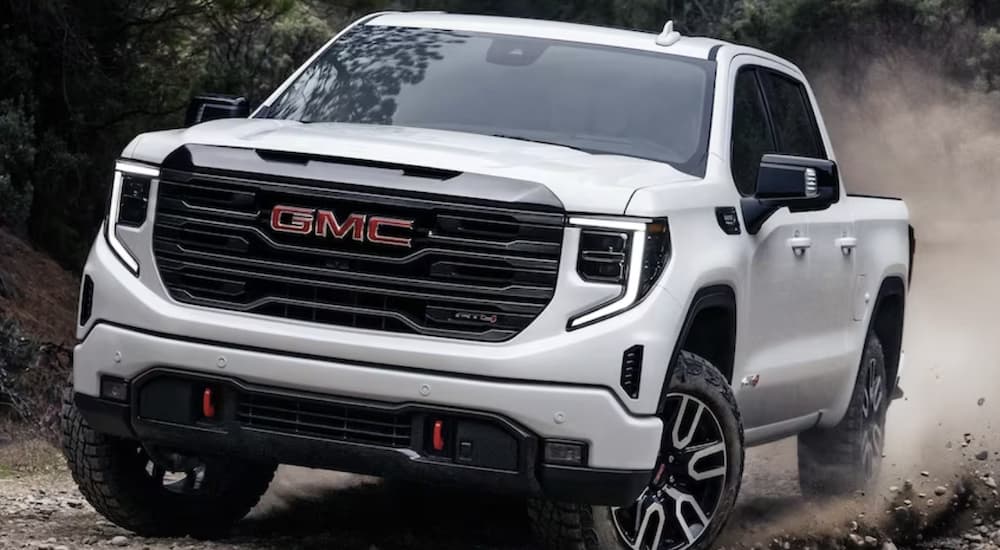 A white 2023 GMC Sierra 1500 AT4 is shown from the front off-roading during a 2023 GMC Sierra 1500 vs 2023 Nissan Titan comparison.