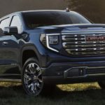 A blue 2023 GMC Sierra 1500 Denali is shown from the front parked in a field.