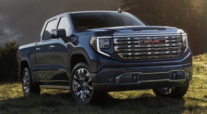 A blue 2023 GMC Sierra 1500 Denali is shown from the front parked in a field.