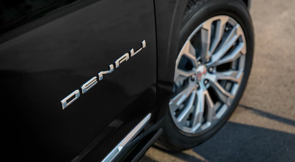 A close up shows the wheel and badge on a black 2023 GMC Yukon Denali Ultimate.