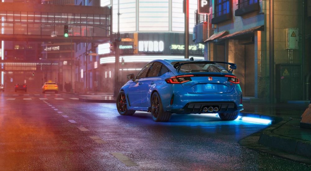 A blue 2023 Honda Civic Type R is shown on a city street at night.